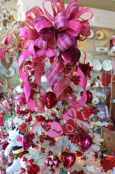 a valentine's day tree decorated with pink, red and white ornaments in a store