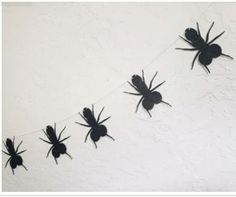 some black bugs are hanging from a string on the wall, and there is no image here to provide a caption for