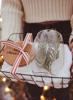 a person holding a basket filled with christmas decorations and wrapped in twine ribbon,