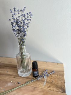 lavender flowers in a glass vase next to an essential oil bottle