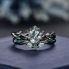 a ring with an aqua green stone in the center and vines around it, sitting on top of a blue box