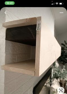 a wooden shelf sitting on top of a white wall next to a potted plant