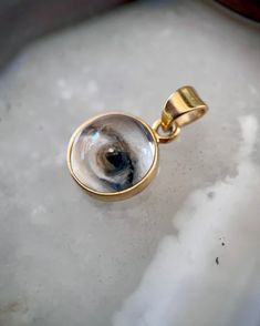 Lover's Eye pendant with an oil painting encased in gold plate over sterling with a quartz crystal cabochon which gives a magical magnifying effect, measuring 1/2" in diameter; 18" 16k gold over brass chain included. THE HISTORY: Lover's Eyes were a jewelry trend c.1785-1830 of brooches set with tiny watercolor portraits on ivory. Since they were cropped to eyes, they were in many ways more direct and intimate than traditional miniature portraits; but also because they were just eyes, they were Gold Mystical Jewelry For Anniversary, Mystical Gold Jewelry For Anniversary, Gold Keepsake Jewelry With Large Pendant, Mystical 14k Gold Jewelry Gift, Mystical Gold Round Pendant Jewelry, Gold Spiritual Jewelry For Keepsake, Round Pendant Jewelry With Rotating Bezel Gift, Rotating Bezel Round Pendant Jewelry As A Gift, Unique Gold Cabochon Jewelry