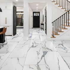 a kitchen with marble floors and stairs in the center, along with an entry way leading to another room