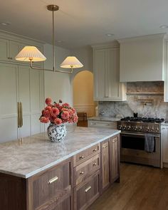 a large kitchen with an island in the middle and two lamps on top of it