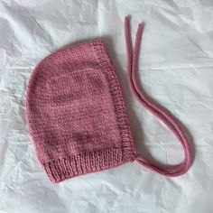 a pink knitted hat laying on top of a white sheet