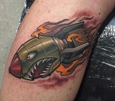 a close up of a person with a tattoo on his arm and the image of a rocket ship in flames