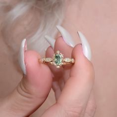 a close up of a person holding a ring with a green stone in the middle