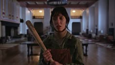 a woman holding a baseball bat in an empty room