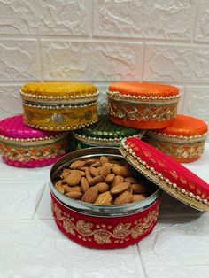 several tins filled with almonds on top of a white tiled floor