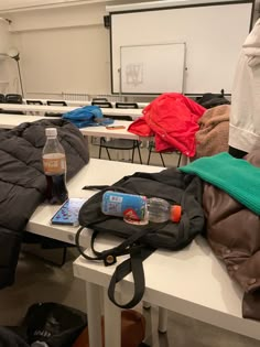 an empty classroom with backpacks and water bottles on the desk