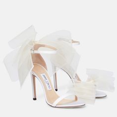 a pair of white high heeled shoes with bows