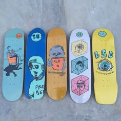 five skateboards are lined up in a row on the concrete floor, one with an image of a man's face