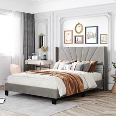 a bedroom with white walls and wood flooring has a large bed in the middle