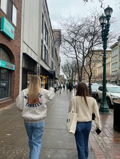 two women walking down the sidewalk in front of stores