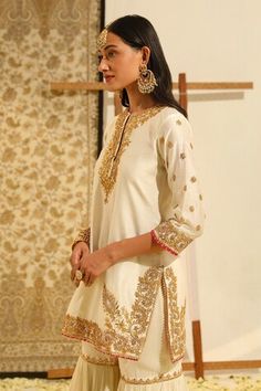 Ivory short silk chanderi kurta with gota patti, dabka, zardozi embroidery in floral pattern. Paired with a gharara with embroidered buttis and dupatta with all over floral jaal embroidery. - Aza Fashions Traditional Cream Sharara With Straight Kurta, Off White Palazzo Set With Zari Work For Festivals, Wedding Palazzo Set With Cutdana On Straight Kurta, Off White Sharara With Cutdana For Diwali, Traditional Cream Palazzo Set For Festive Occasions, Off White Cutdana Sharara For Diwali, Festive Cream Sharara With Gota Work, Off-white Palazzo Set With Zari Work For Festivals, Off-white Cutdana Sharara For Diwali