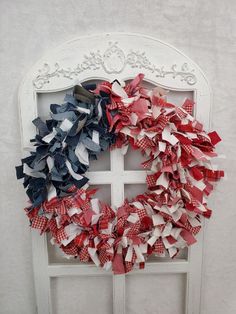 a wreath made out of red, white and blue ribbons is hanging on a door