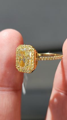 a person holding a yellow diamond ring in their hand