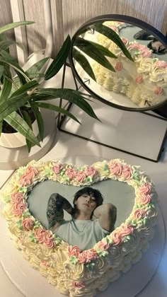 a heart shaped cake sitting on top of a table next to a potted plant