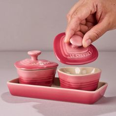 a person is pouring something into a pink container with two bowls on the bottom and one bowl in the middle