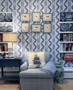 a living room with blue and white wallpaper, furniture and bookshelves in it