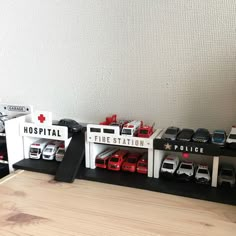 toy cars are lined up on display in a room with white walls and wood flooring