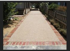 the walkway is lined with red bricks and green bushes on either side of the house