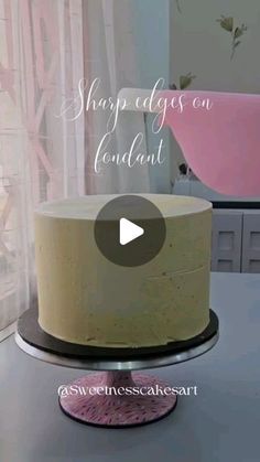 a white cake sitting on top of a table next to a pink tub and window