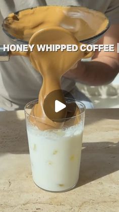 a person pouring milk into a glass with the words honey whipped coffee mix in it