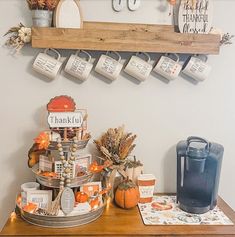 a wooden table topped with lots of fall decorations and coffee mugs on top of it