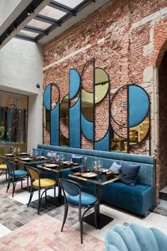 the interior of a restaurant with blue booths and tables in front of an arched window