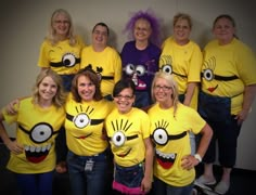 a group of people wearing yellow shirts with faces painted on them posing for a photo