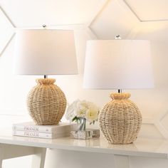 two wicker lamps sitting on top of a white table next to a vase with flowers