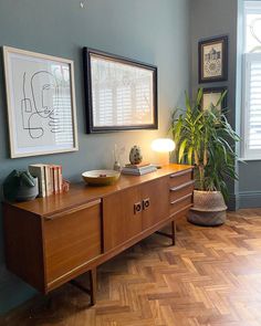 a living room with wood flooring and blue walls, two framed pictures on the wall