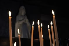 many lit candles in front of a statue