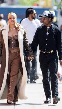 a man and woman walking down the street holding hands