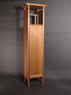 a tall wooden cabinet sitting on top of a black floor next to a gray wall