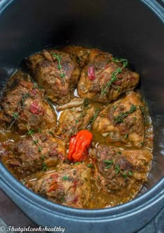 some meat and vegetables are cooking in a slow cooker with red peppers on the side