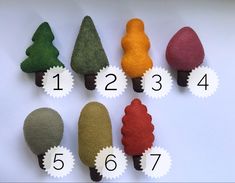 felt trees are arranged in different colors and sizes on a white surface with numbers for each one