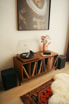 a record player sitting on top of a wooden shelf next to a painting and rug