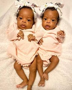 two babies laying next to each other on a white blanket