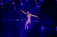 a woman is performing on stage with her arms outstretched