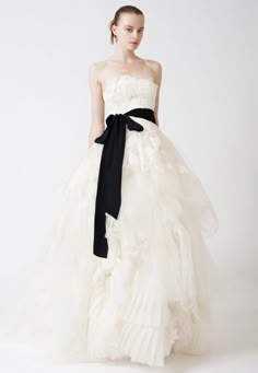 a woman in a white dress with a black bow on her waist and the words vera wang ella dress