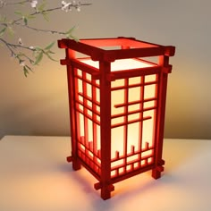 a red lantern sitting on top of a table next to a tree branch with white flowers