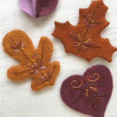 four felt leaves are arranged on a white surface, one is purple and the other is orange