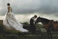 a man standing next to a woman in a white dress near a horse on a hill