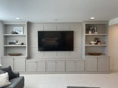 a living room filled with furniture and a flat screen tv mounted on the wall above it