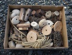 a box filled with lots of different types of wood and rope on top of rocks