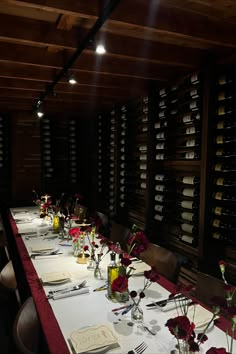 a long table is set with wine bottles and flowers