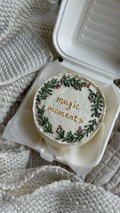 a decorated cake in a white box on top of a blanket with the words magic moments written on it